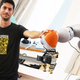 PhD student Lucas Manuelli poses with a Kuka robot arm, which uses a neural net to learn about new objects.